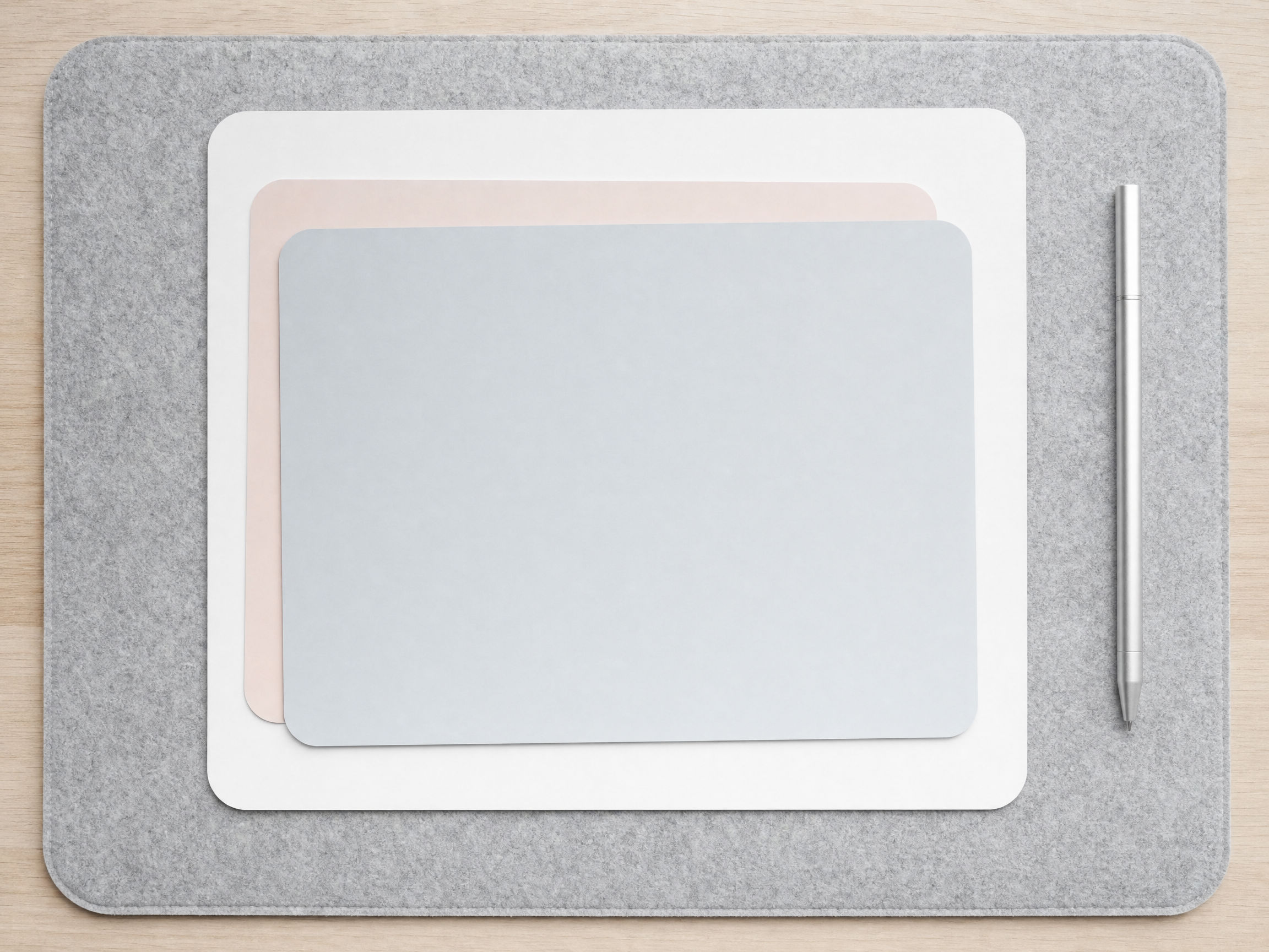 Nested rounded sheets — white, blush, and fog — stacked on a gray felt blotter.